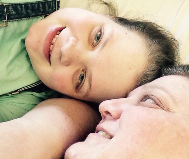Fourteen year old Tiegan Elise lays next to her mum in a hospital bed; her mother gazes into her eyes.
