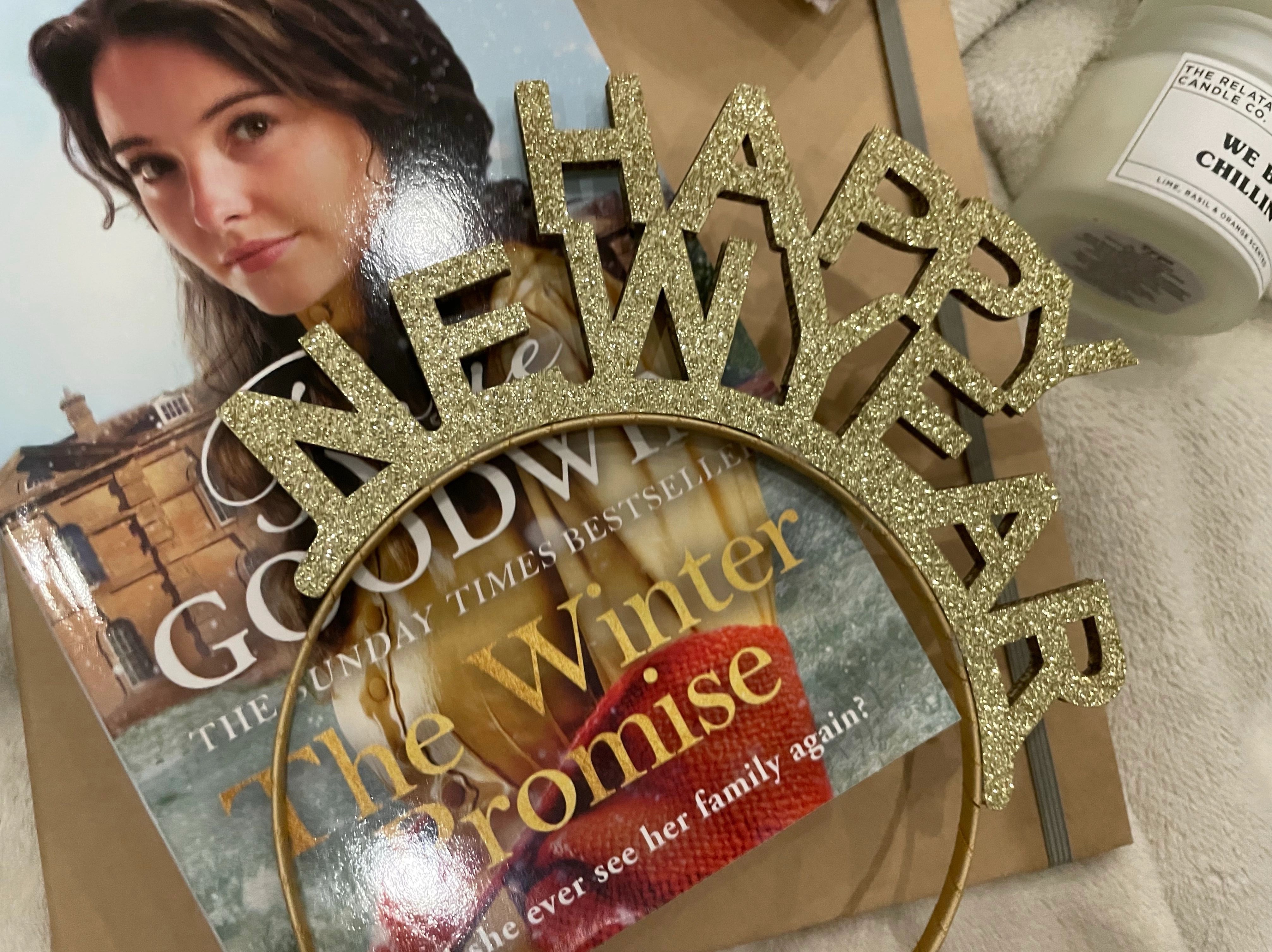 A “Happy New Year” headband, Rosie Goodwin’s “A Winter’s Promise” and other items lay on a blanket.