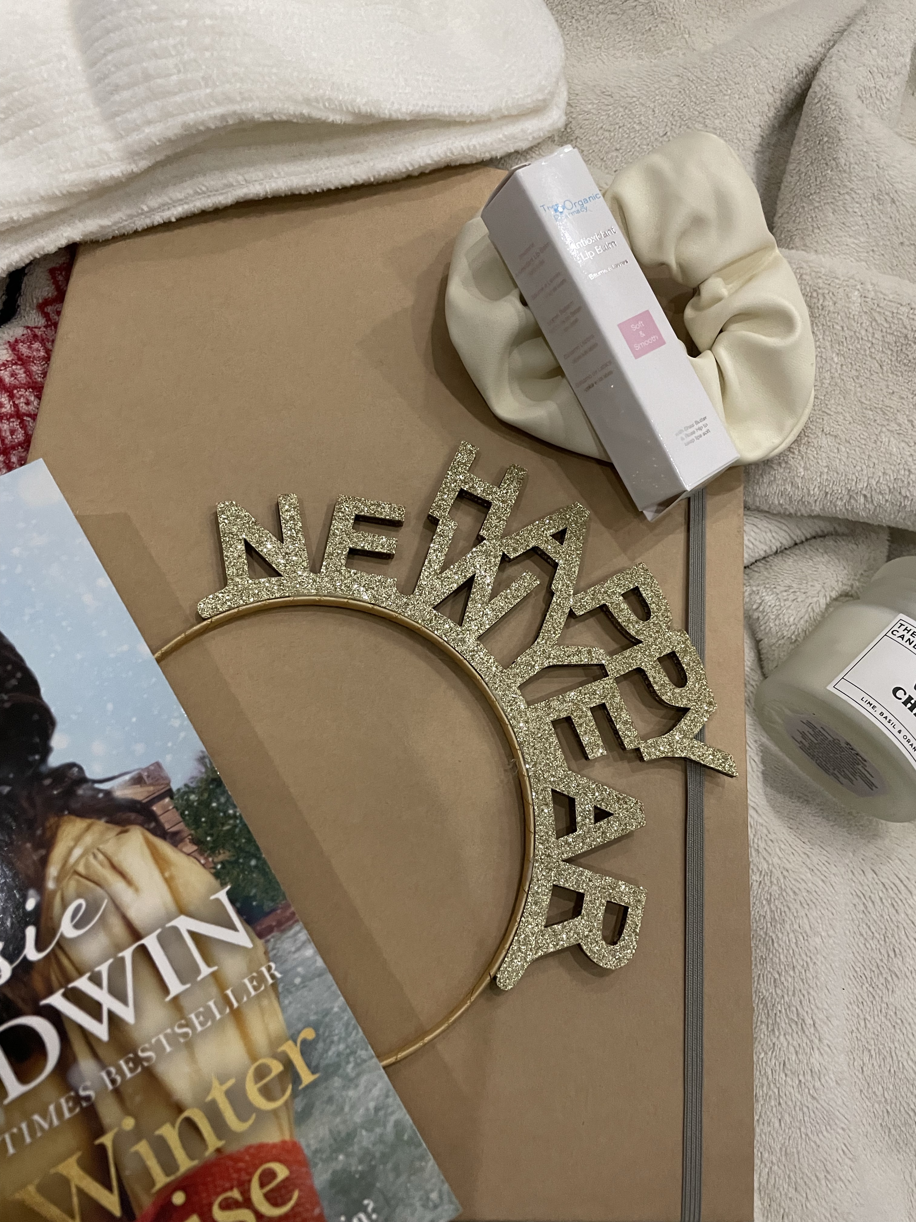 A “Happy New Year” headband, Rosie Goodwin’s “A Winter’s Promise” and other items lay on a blanket.