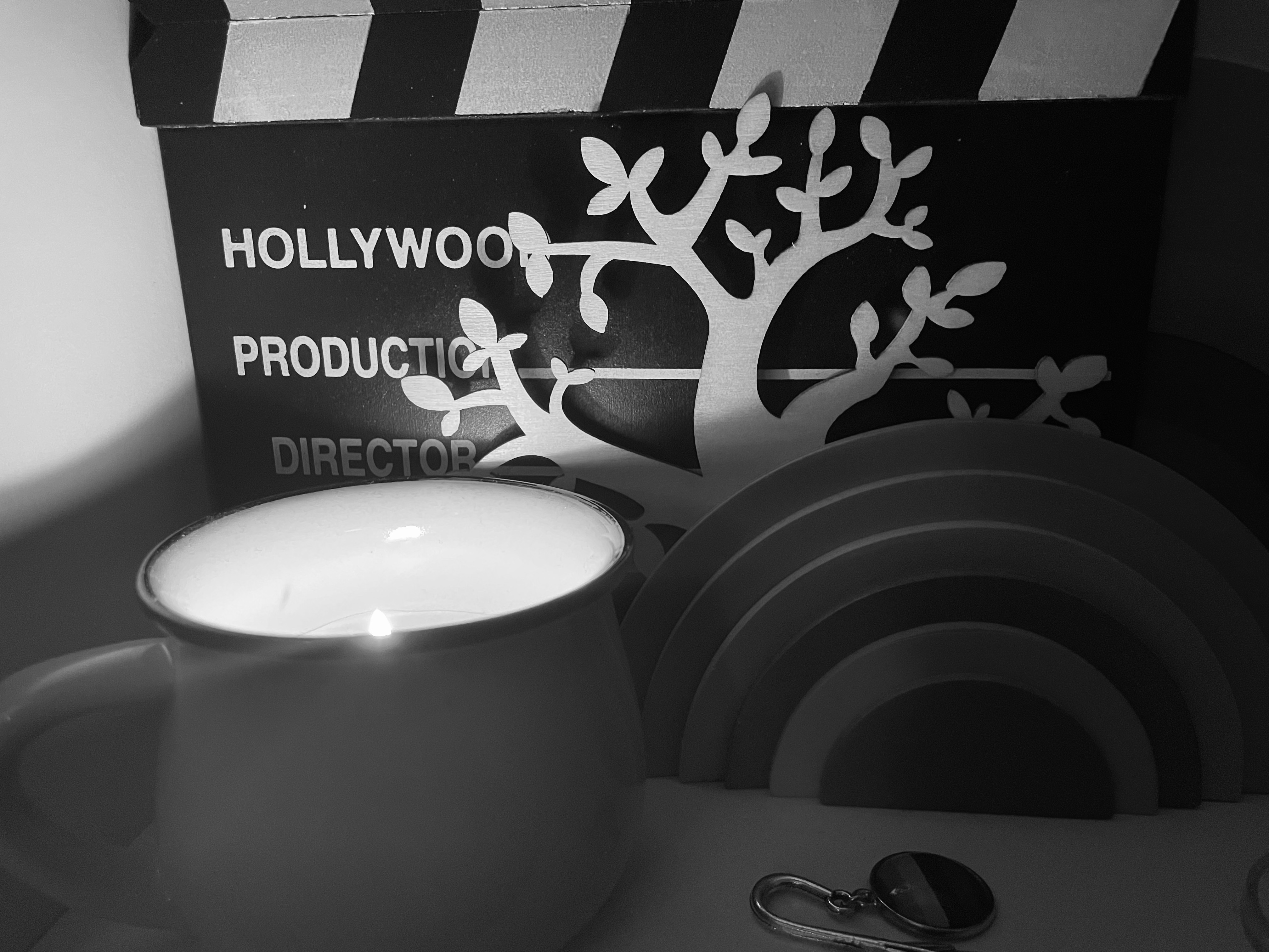 A candle on a shelf with ornaments in black and white.