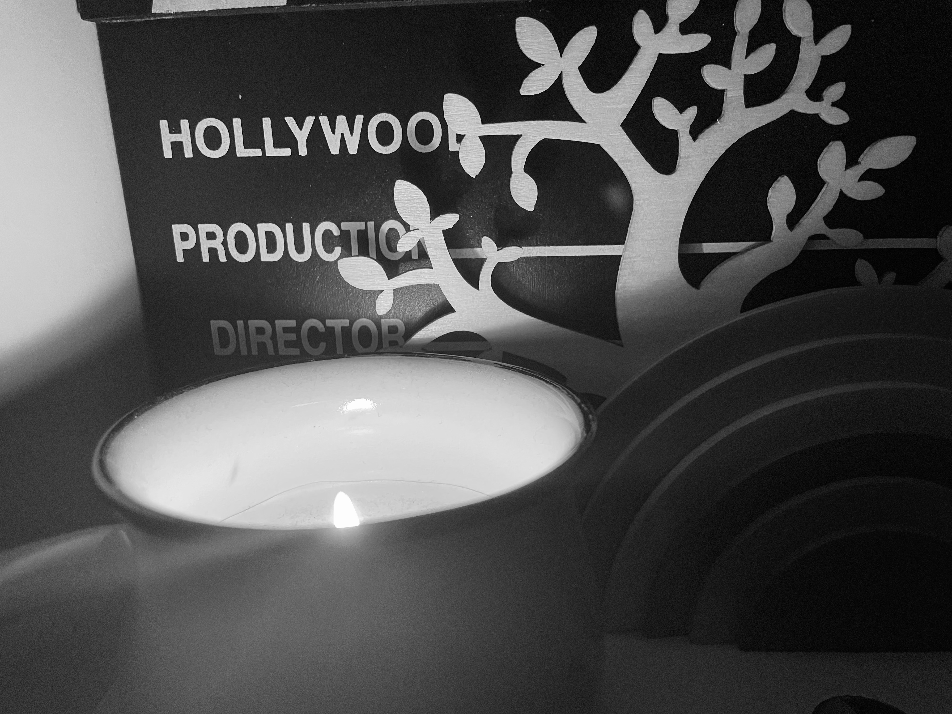A candle on a shelf with ornaments in black and white.