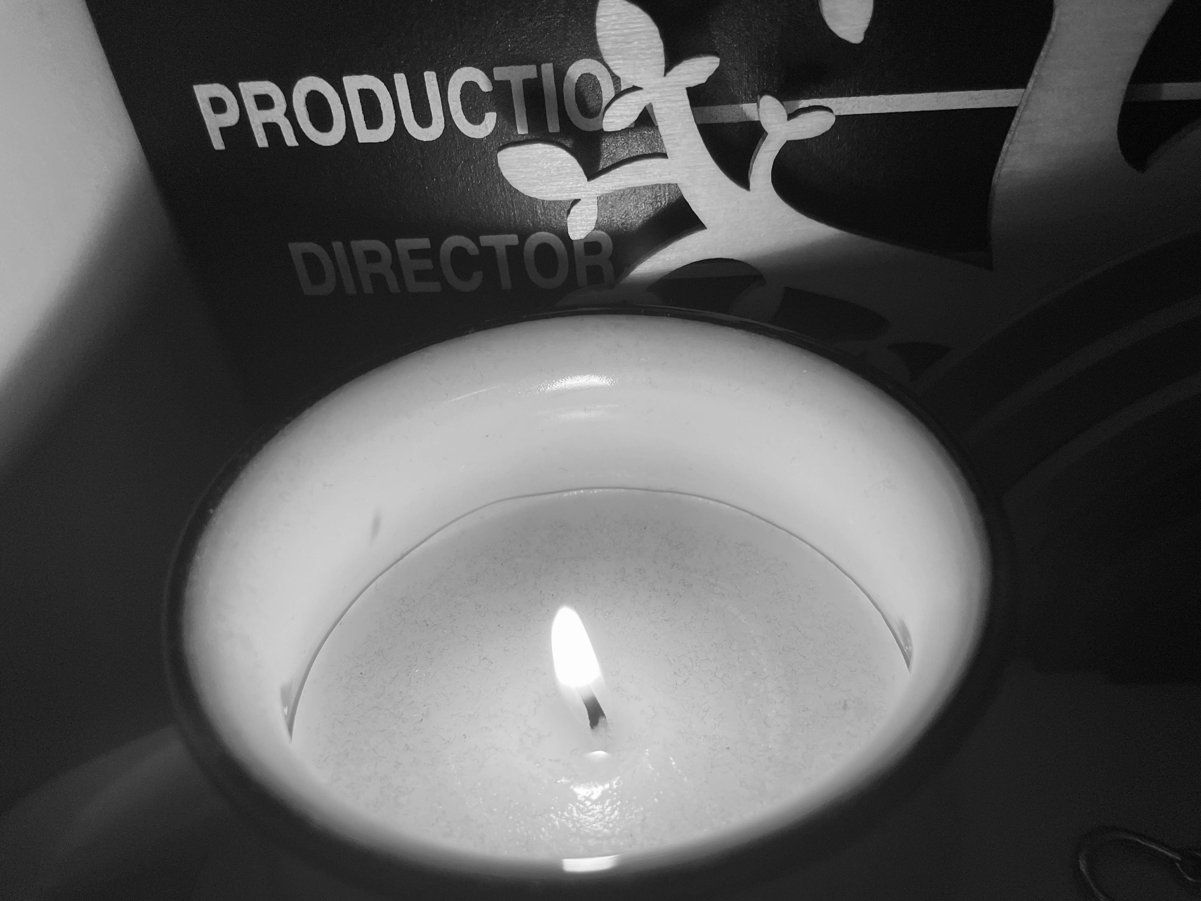 A candle on a shelf with ornaments in black and white.