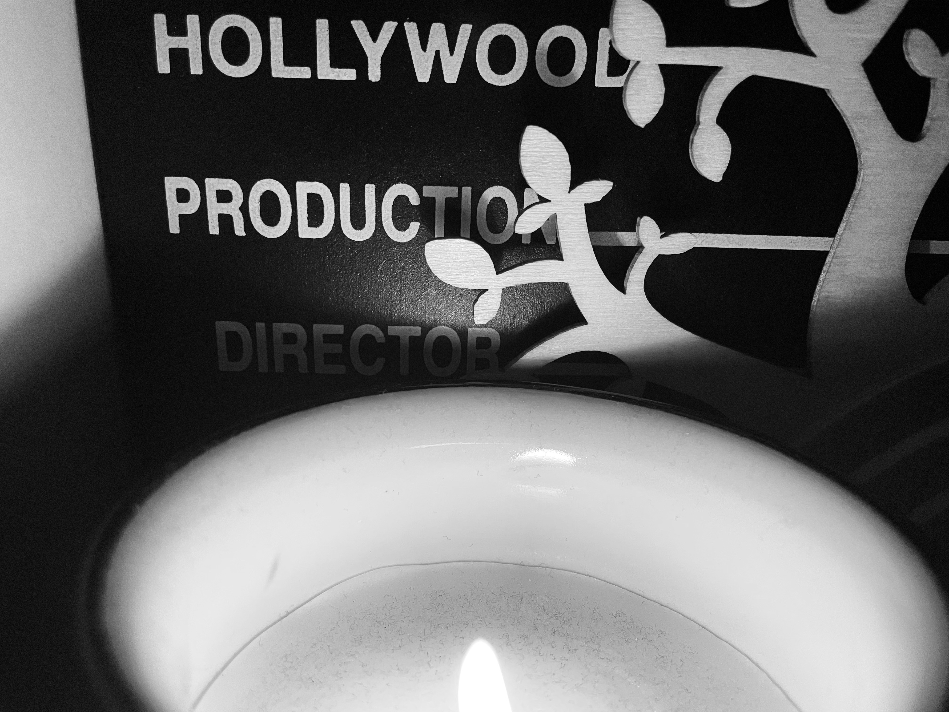 A candle on a shelf with ornaments in black and white.