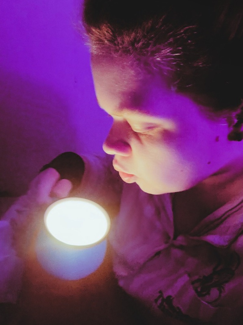 Tig holds a mug candle that they pierce their lips ready to blow out 