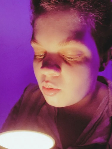 Tig holds a mug candle that they pierce their lips ready to blow out 