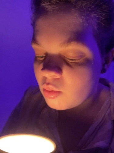 Tig holds a mug candle that they pierce their lips ready to blow out 