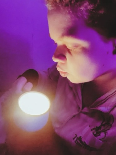 Tig holds a mug candle that they pierce their lips ready to blow out 