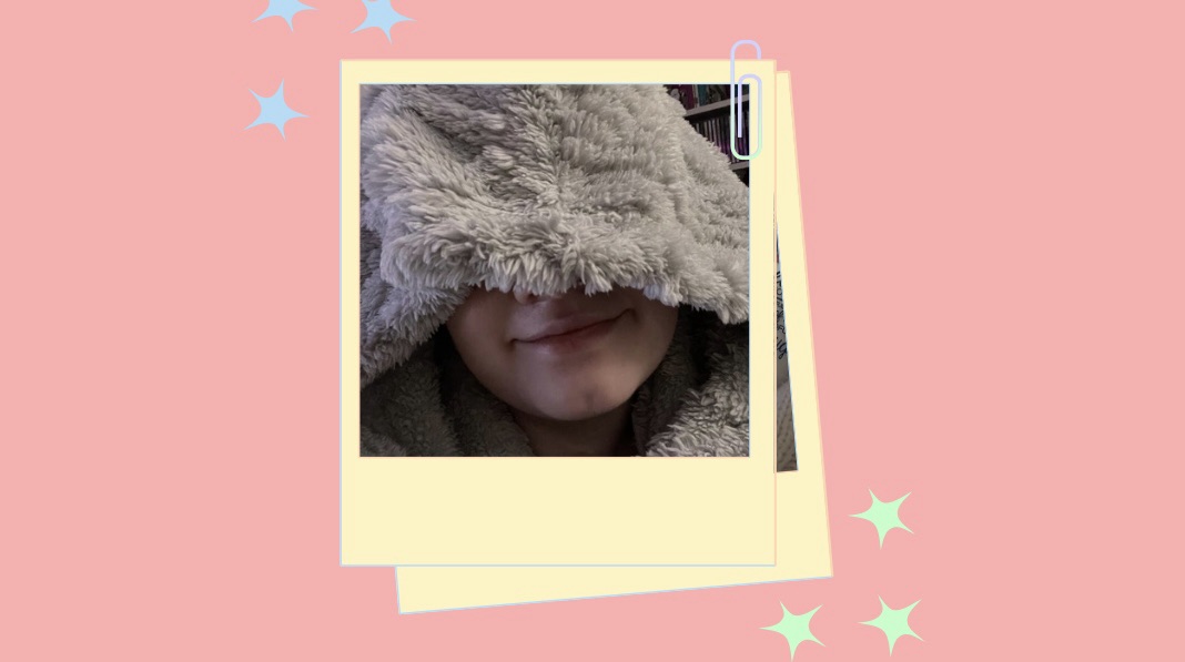 A cartoon style polaroid of Tig partially hidden under a fluffy hood, showing only their smiling mouth and chin. The background features a light red setting with cartoon stars.